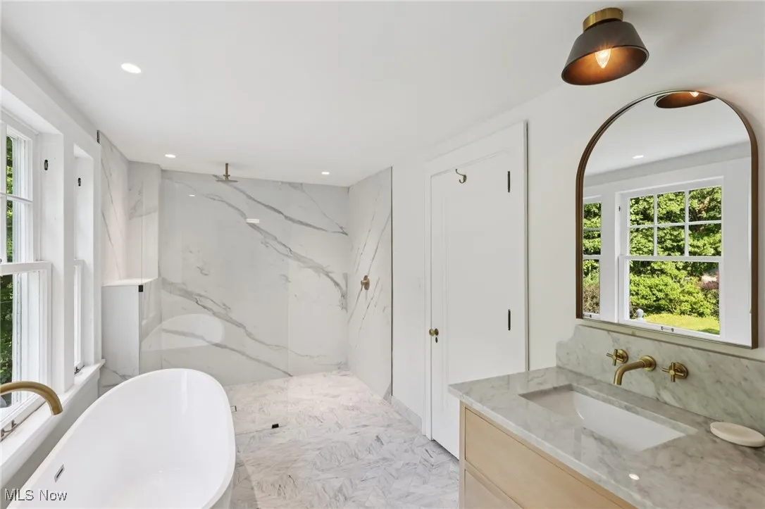 Full bathroom featuring plenty of natural light, a marble finish shower, a soaking tub, vanity, and recessed lighting