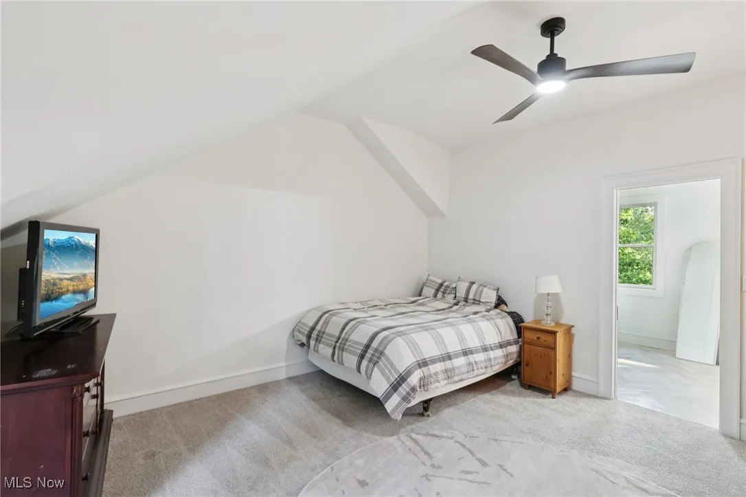 Bedroom with light colored carpet, a ceiling fan, and vaulted ceiling