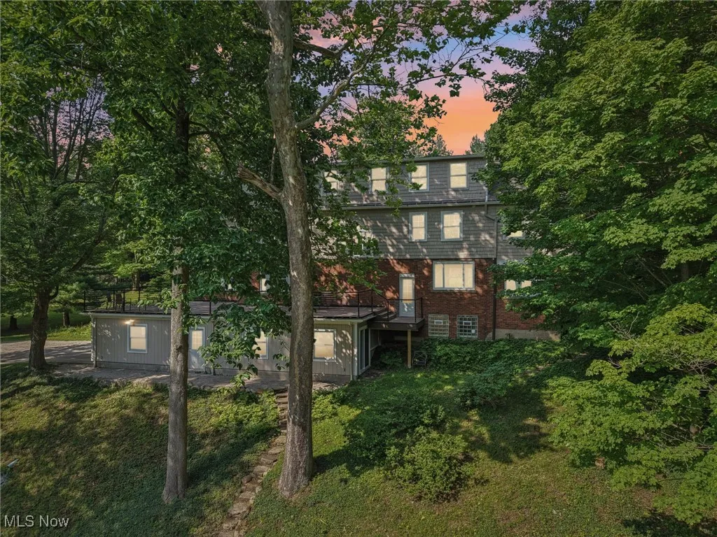 Back of property at dusk with brick siding and a lawn