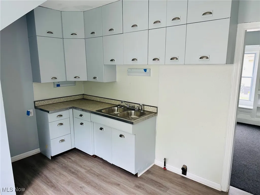 Kitchen with light wood-style flooring, dark countertops, and white cabinetry