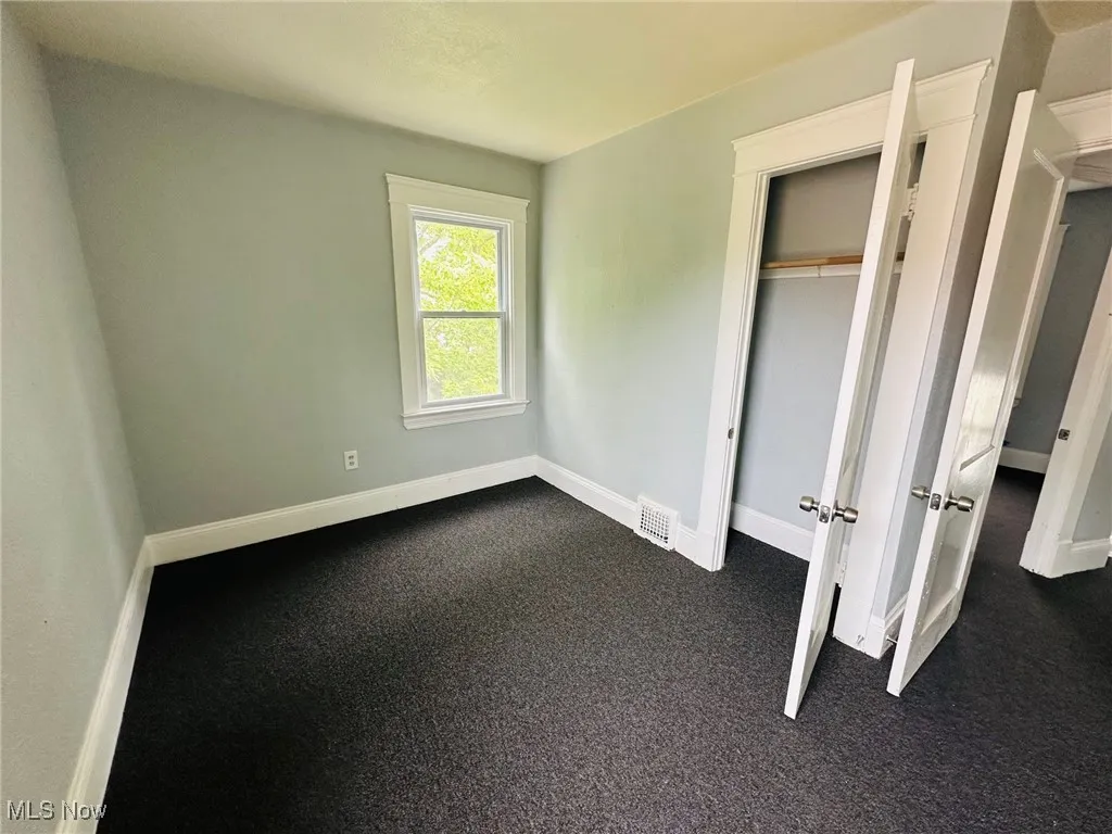Unfurnished bedroom with dark carpet and a closet