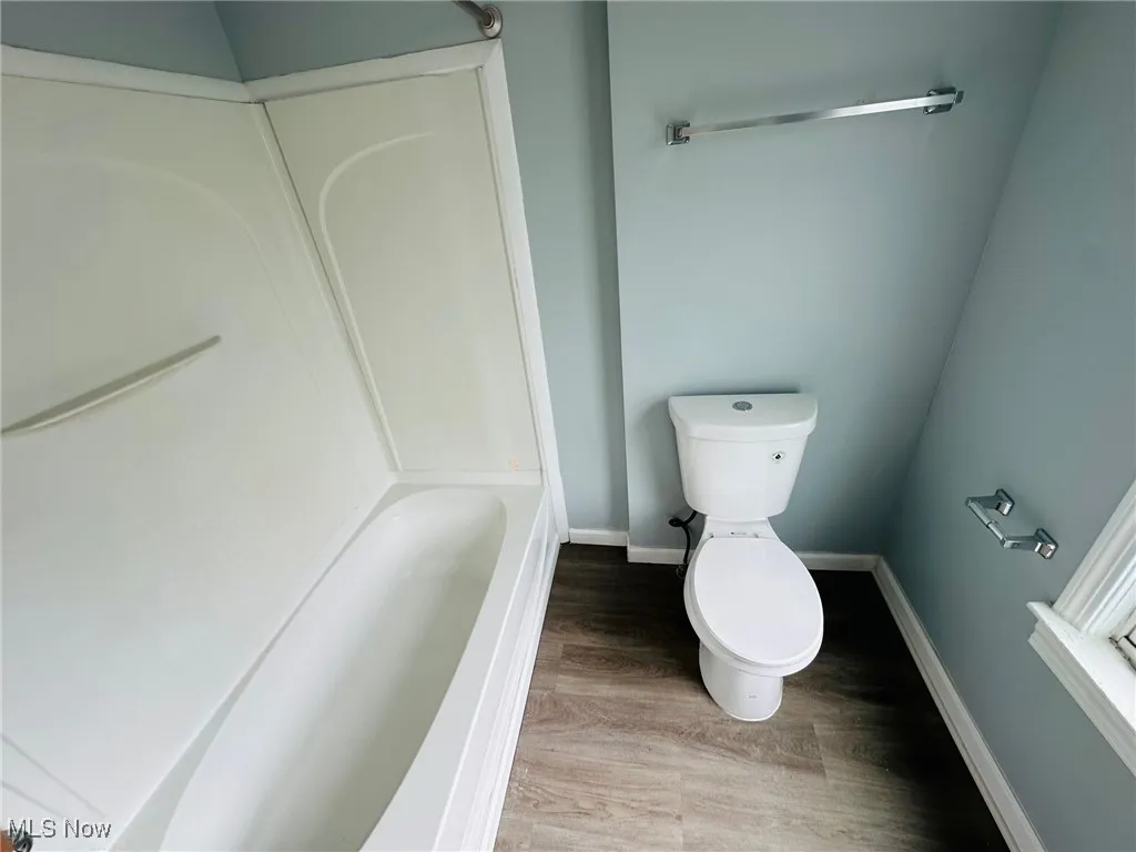 Full bath with a tub to relax in, wood finished floors, and a shower