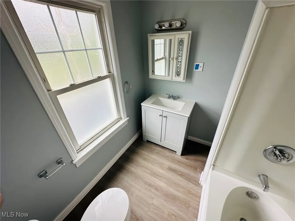 Full bath with a bathtub, vanity, and wood finished floors