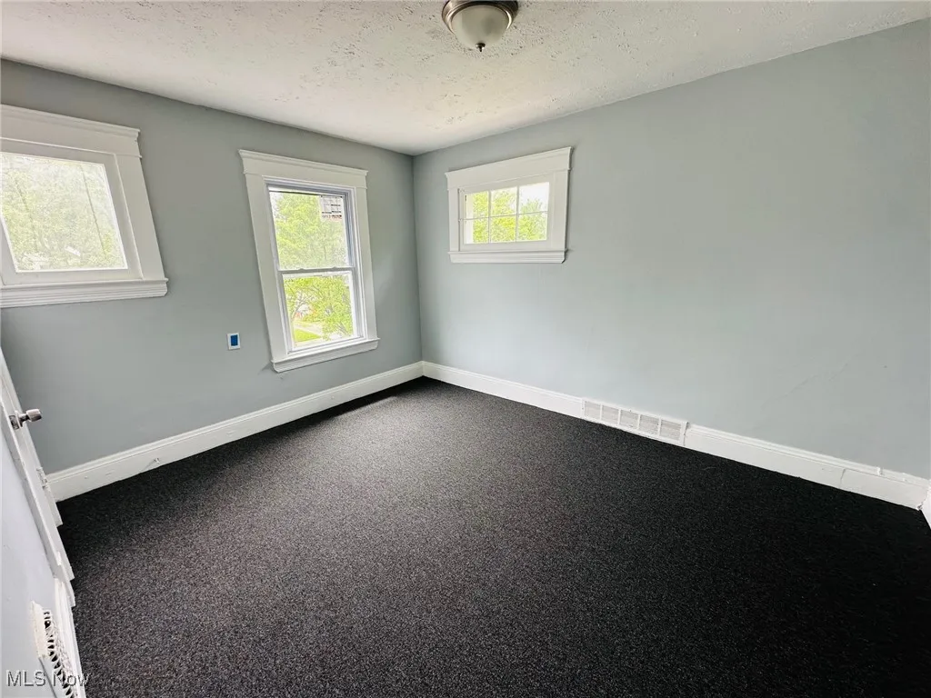 Empty room with baseboards and a textured ceiling