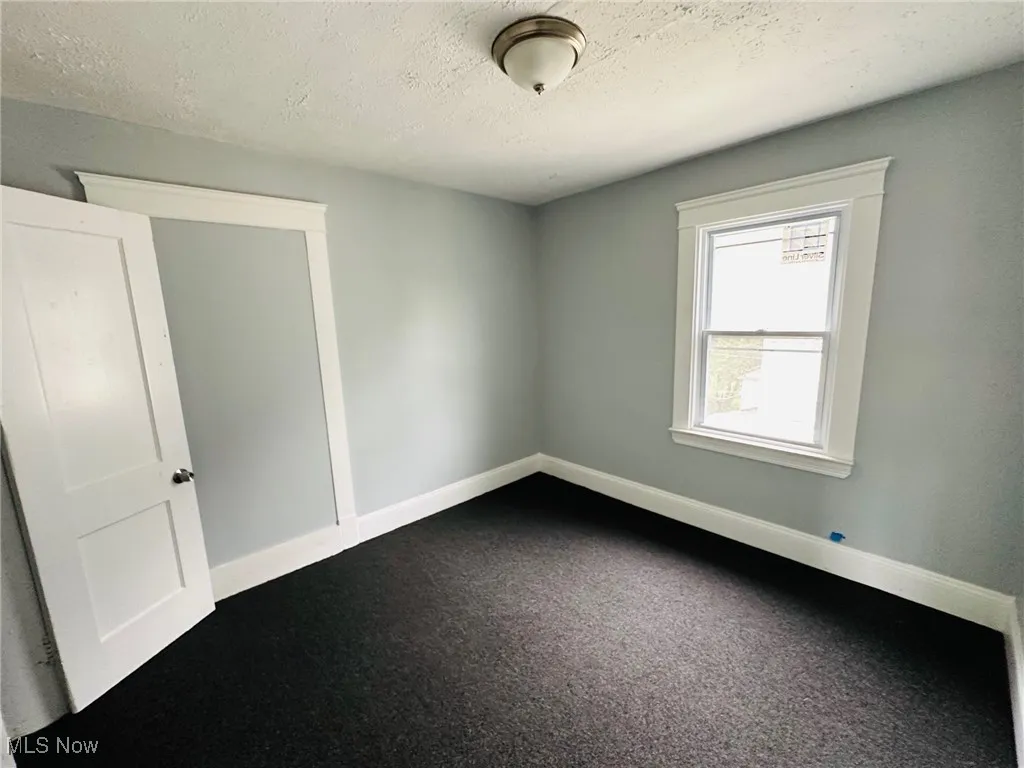 Empty room featuring a textured ceiling and dark carpet