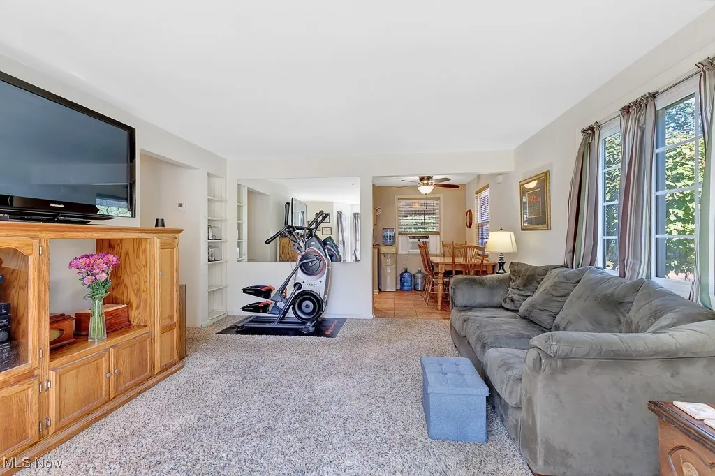 Carpeted living area featuring healthy amount of natural light, built in features, a ceiling fan, and cooling unit