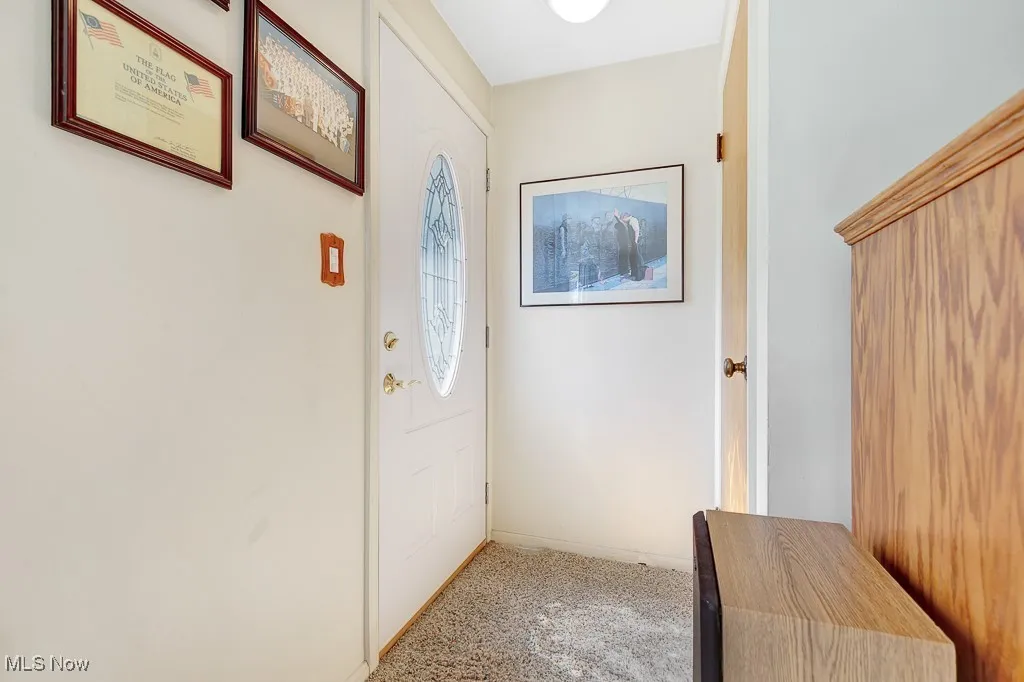 Doorway to outside featuring light colored carpet