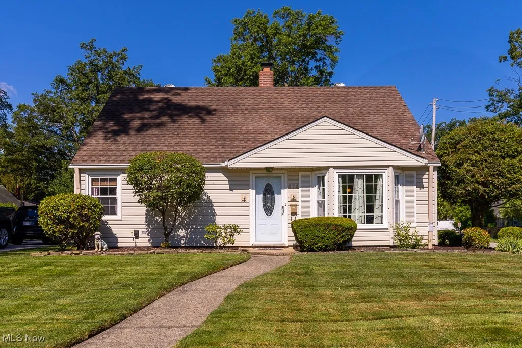 View of front of property featuring a chimney, a front yard, a shingled roof, and french doors