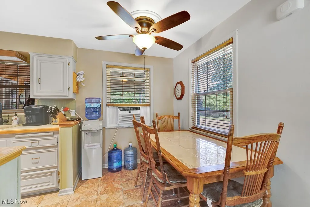 Dining space featuring ceiling fan, cooling unit, and light stone finish floors