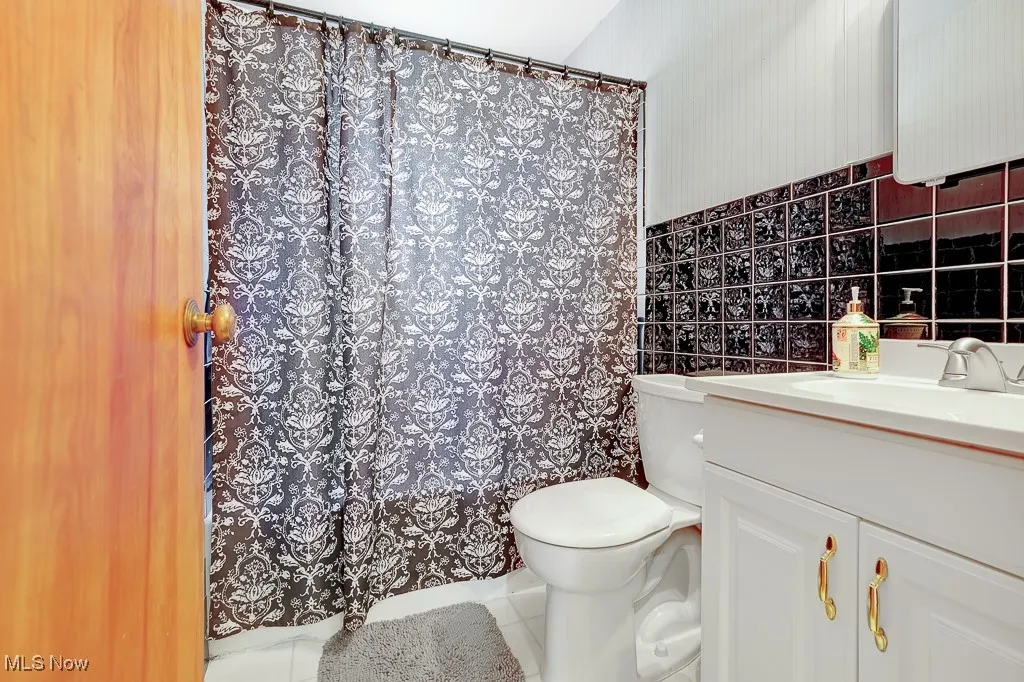 Bathroom with vanity, tile walls, tile patterned flooring, and curtained shower