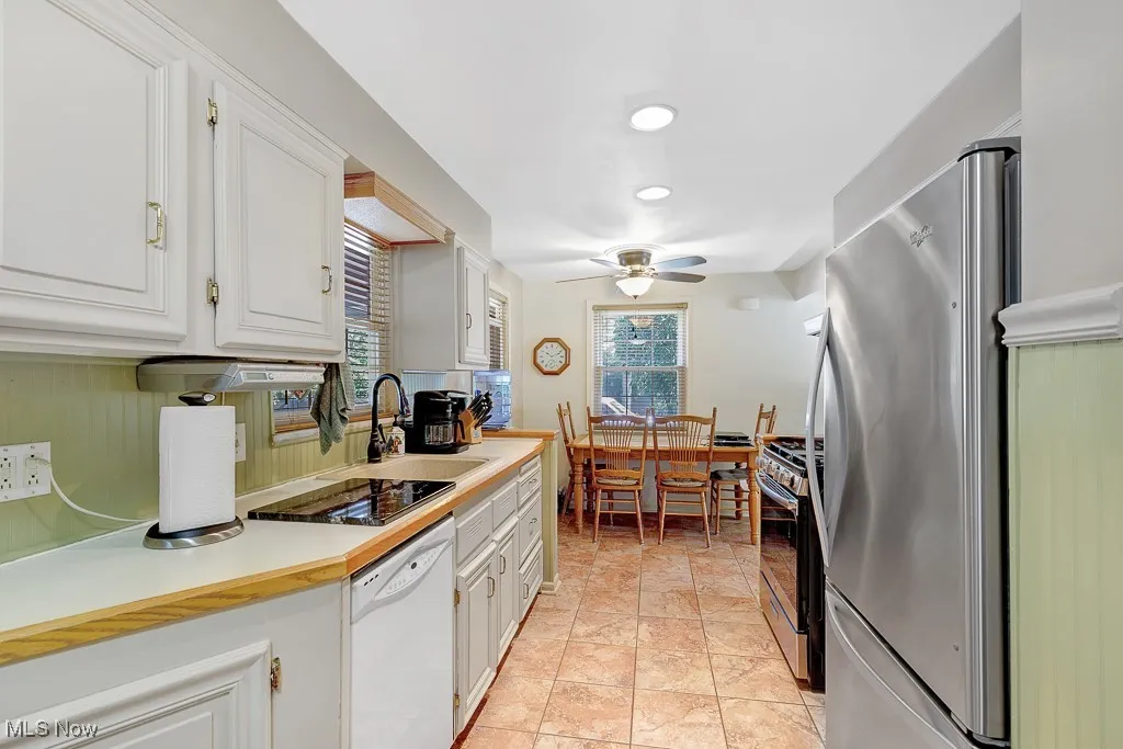 Kitchen featuring stainless steel appliances, a ceiling fan, white cabinetry, light countertops, and recessed lighting