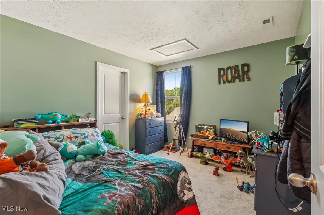Carpeted bedroom with attic access and a textured ceiling