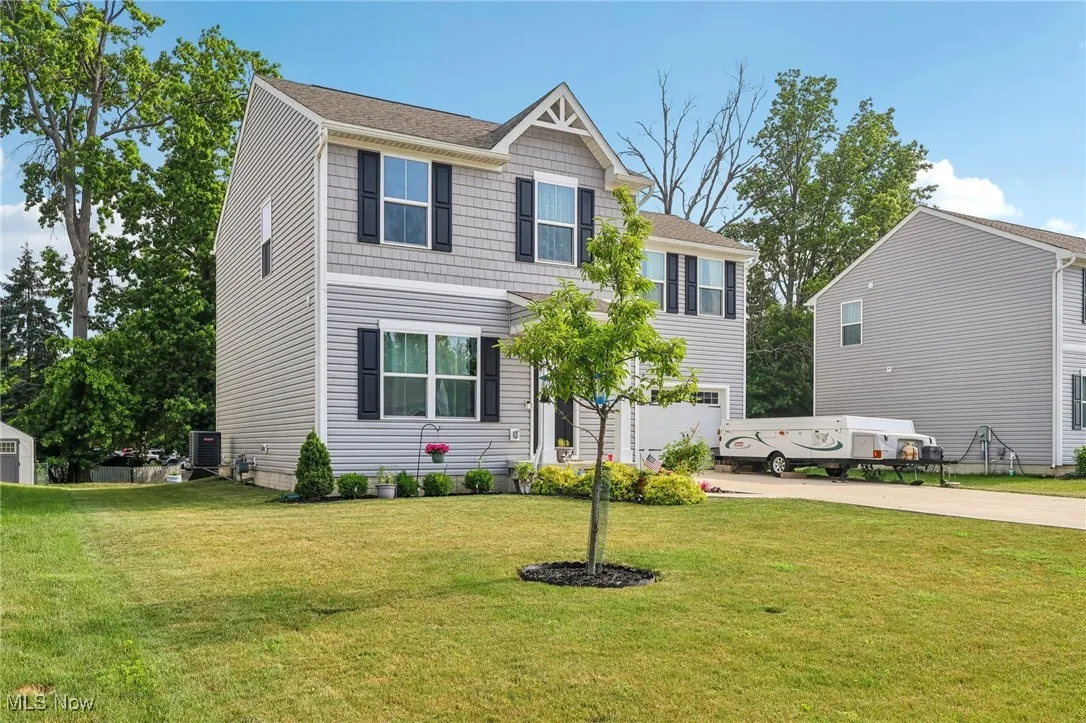 View of front facade featuring concrete driveway, a front yard, a garage, and a shingled roof