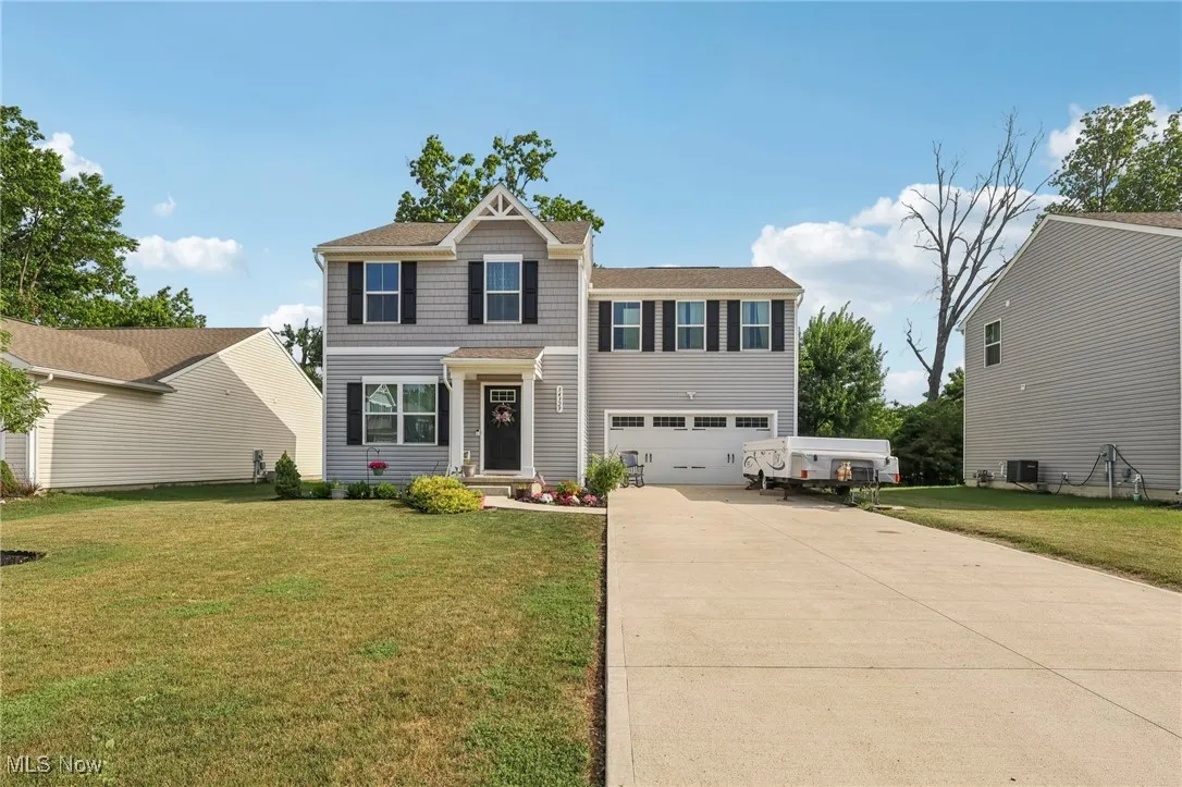 View of front of property featuring concrete driveway, an attached garage, and a front lawn