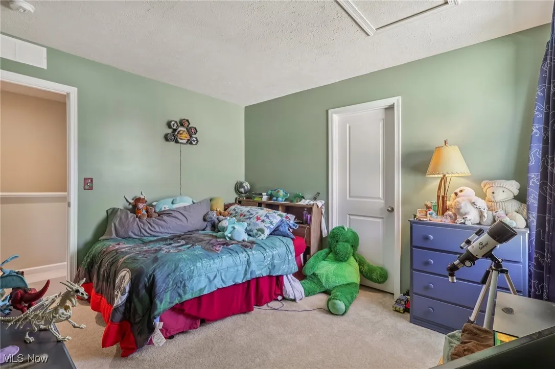 Bedroom featuring carpet flooring, attic access, and a textured ceiling
