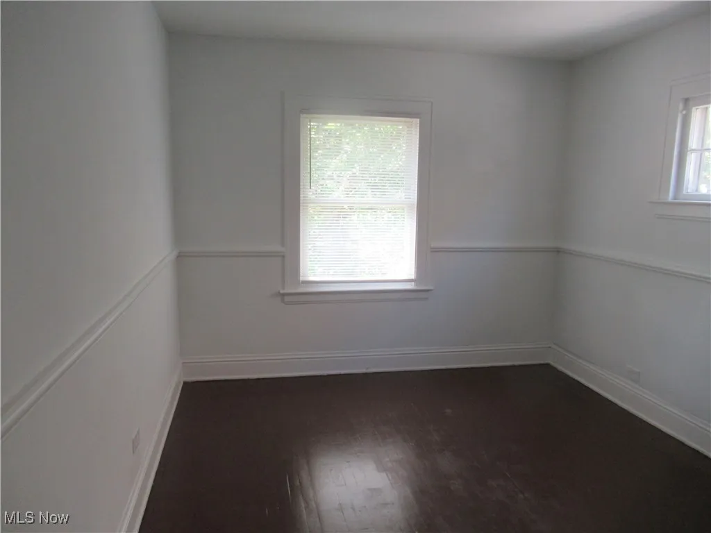 Empty room featuring baseboards and dark wood-style floors