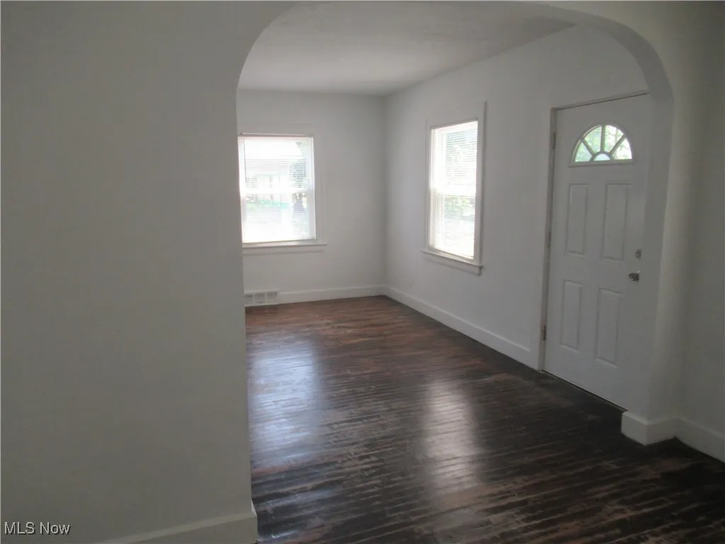 Entryway with arched walkways and dark wood-style flooring