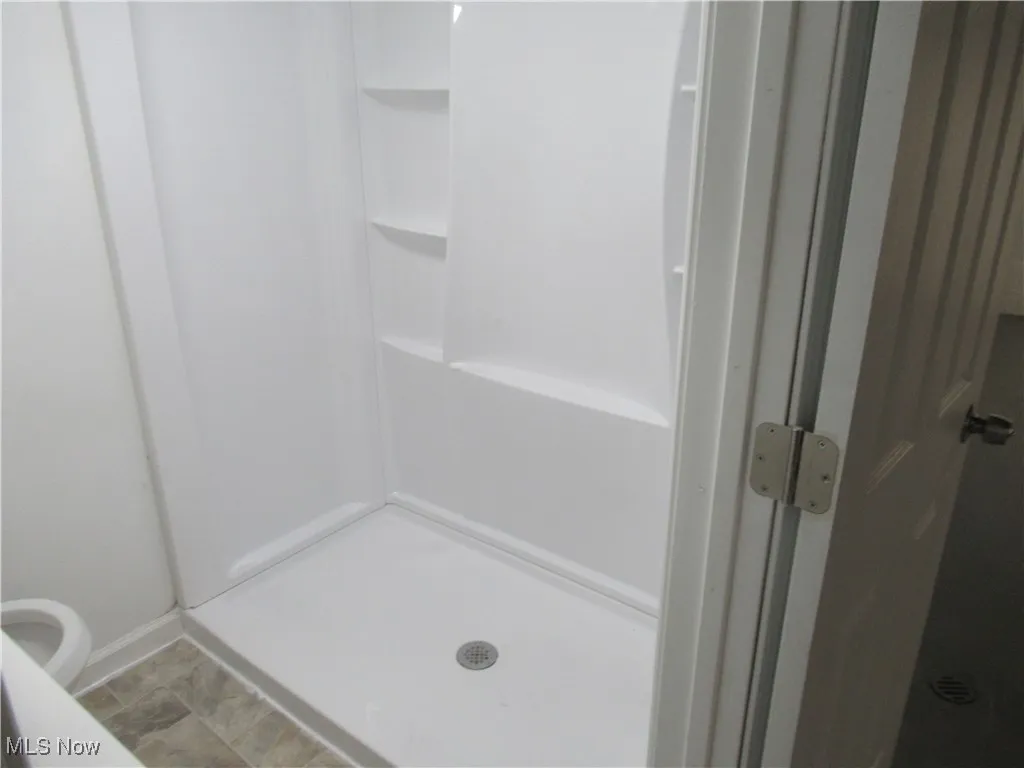 Full bathroom featuring a shower stall and baseboards