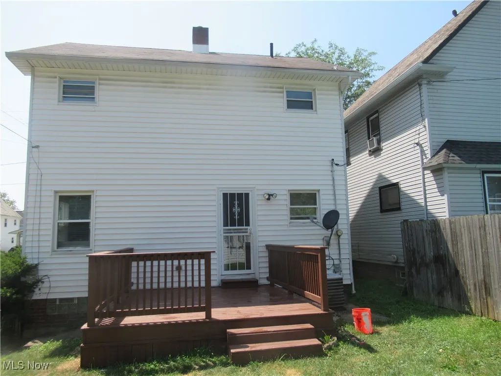 Back of house featuring a deck, a chimney, and cooling unit