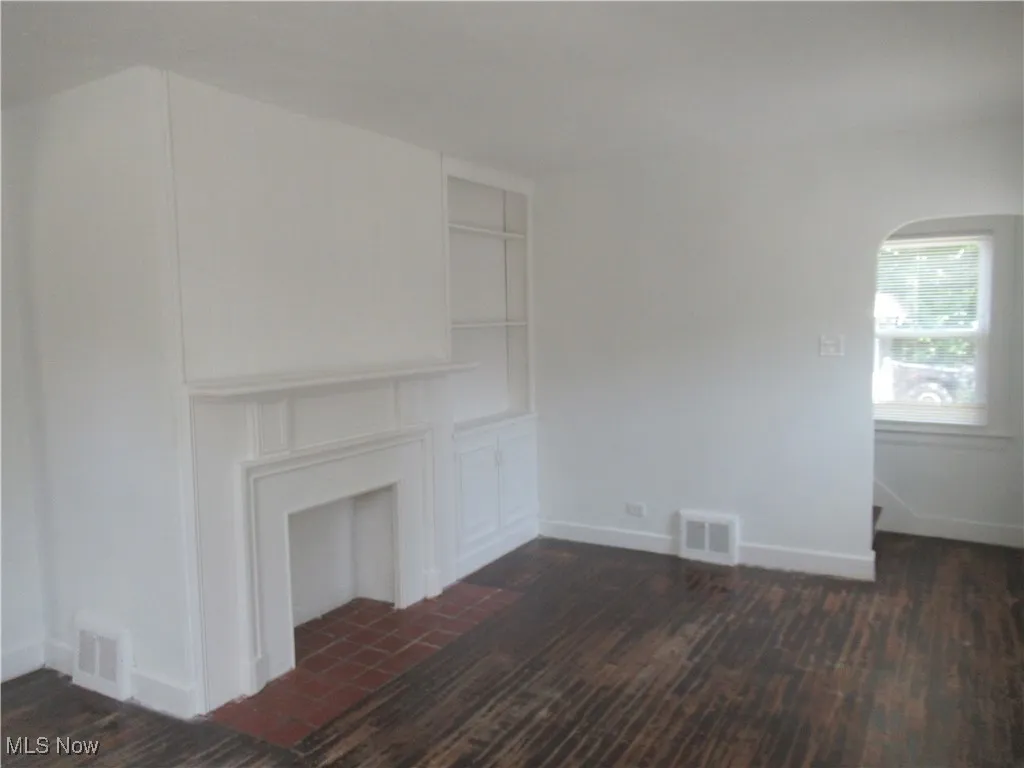 Unfurnished living room with dark wood-style floors and arched walkways