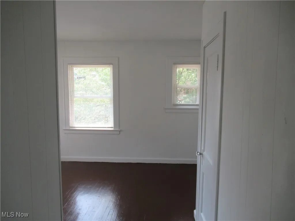 Empty room with dark wood-style flooring and wooden walls