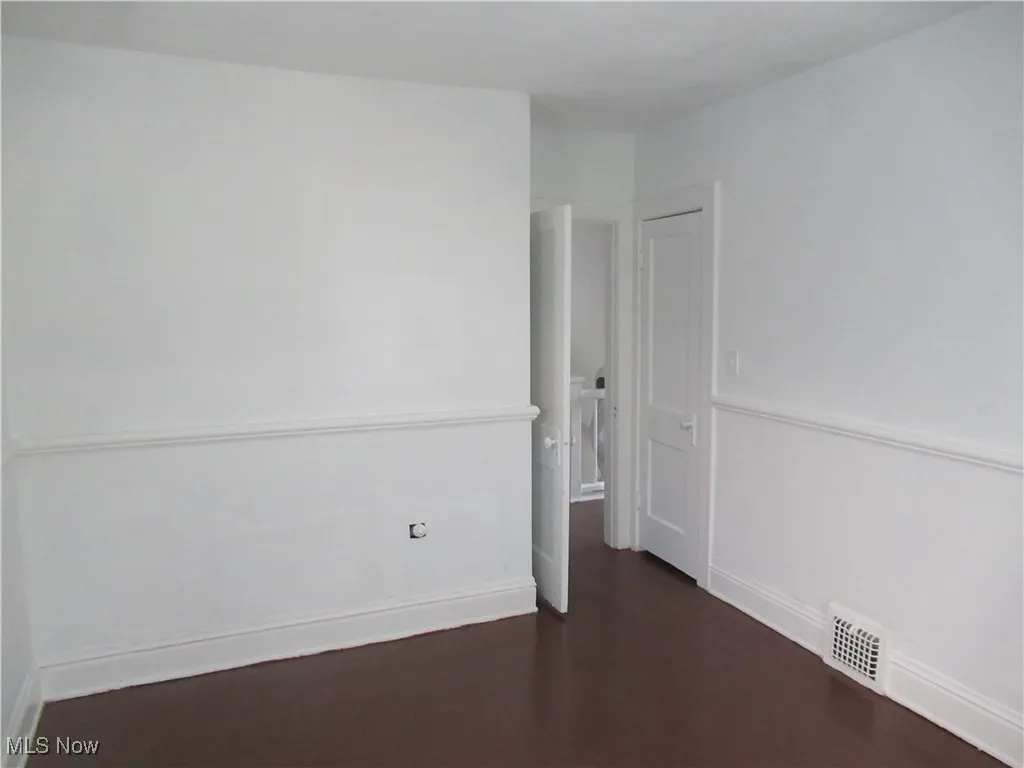 Spare room featuring baseboards and dark wood-style floors