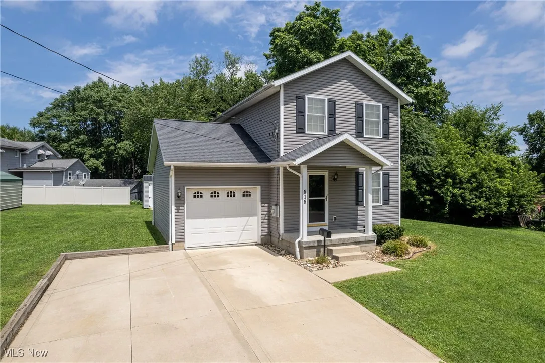 Traditional-style house with a garage, driveway, and a porch