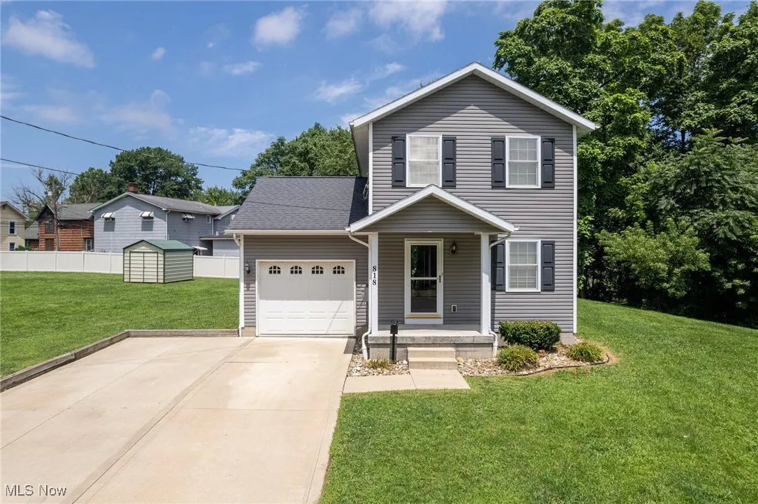 View of front facade featuring a garage, a shed, and concrete driveway