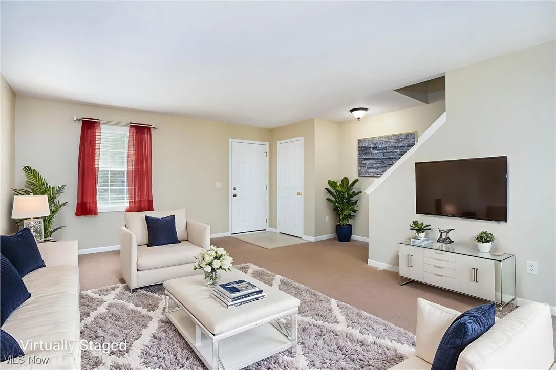 Carpeted living room featuring baseboards and stairway