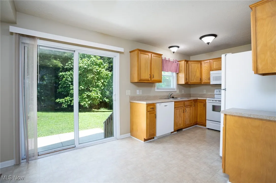 Kitchen with white appliances, light countertops, and plenty of natural light