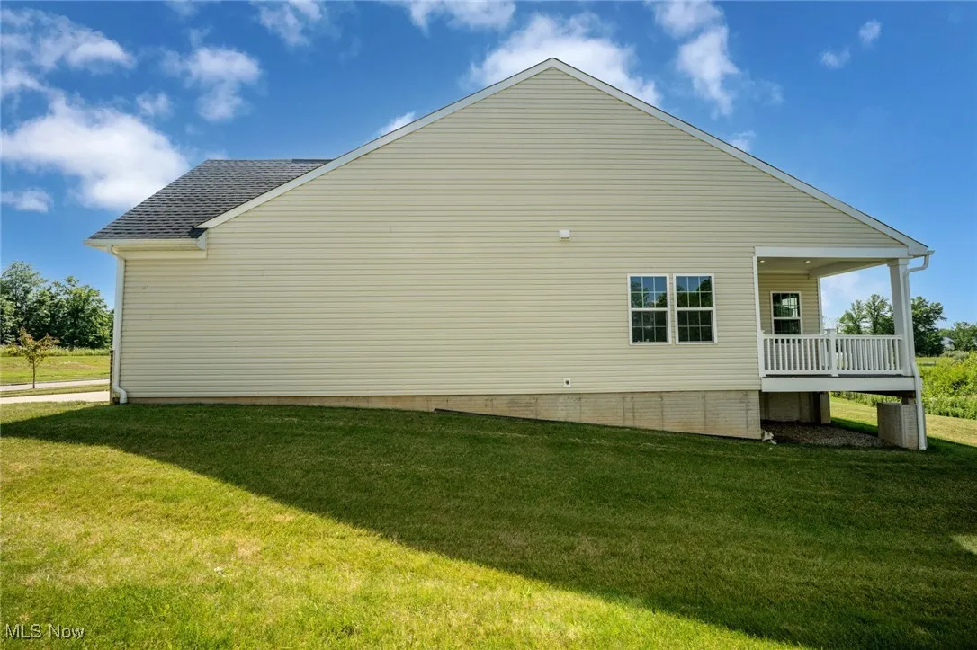 View of side of property featuring a yard and a shingled roof