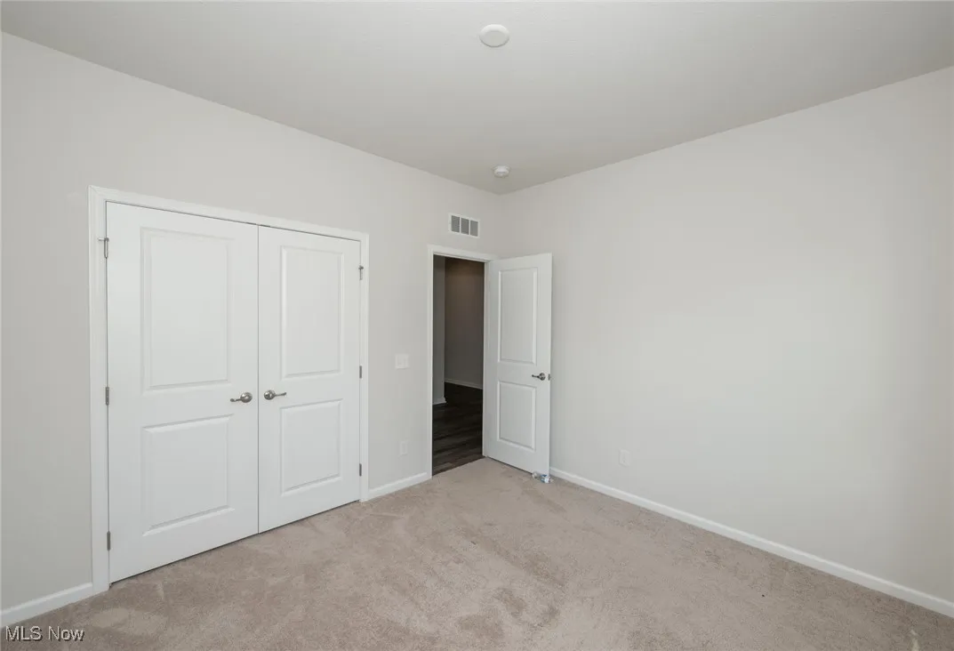 Unfurnished bedroom with light colored carpet and a closet