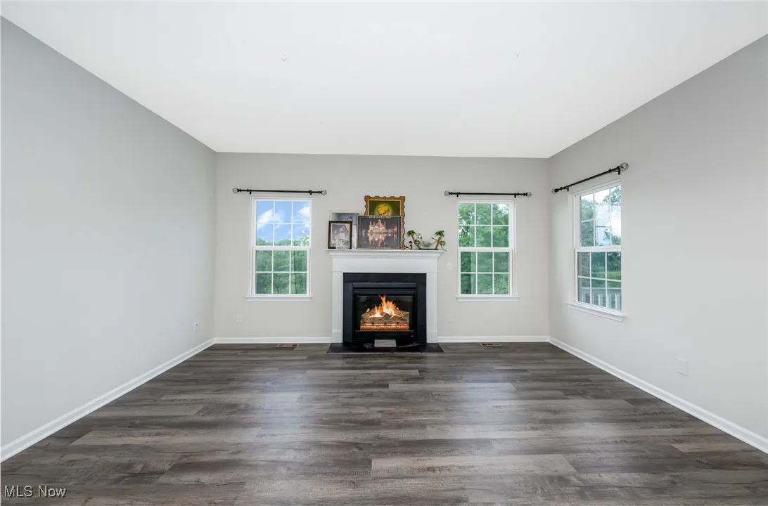Unfurnished living room with a fireplace with flush hearth and dark wood-style flooring