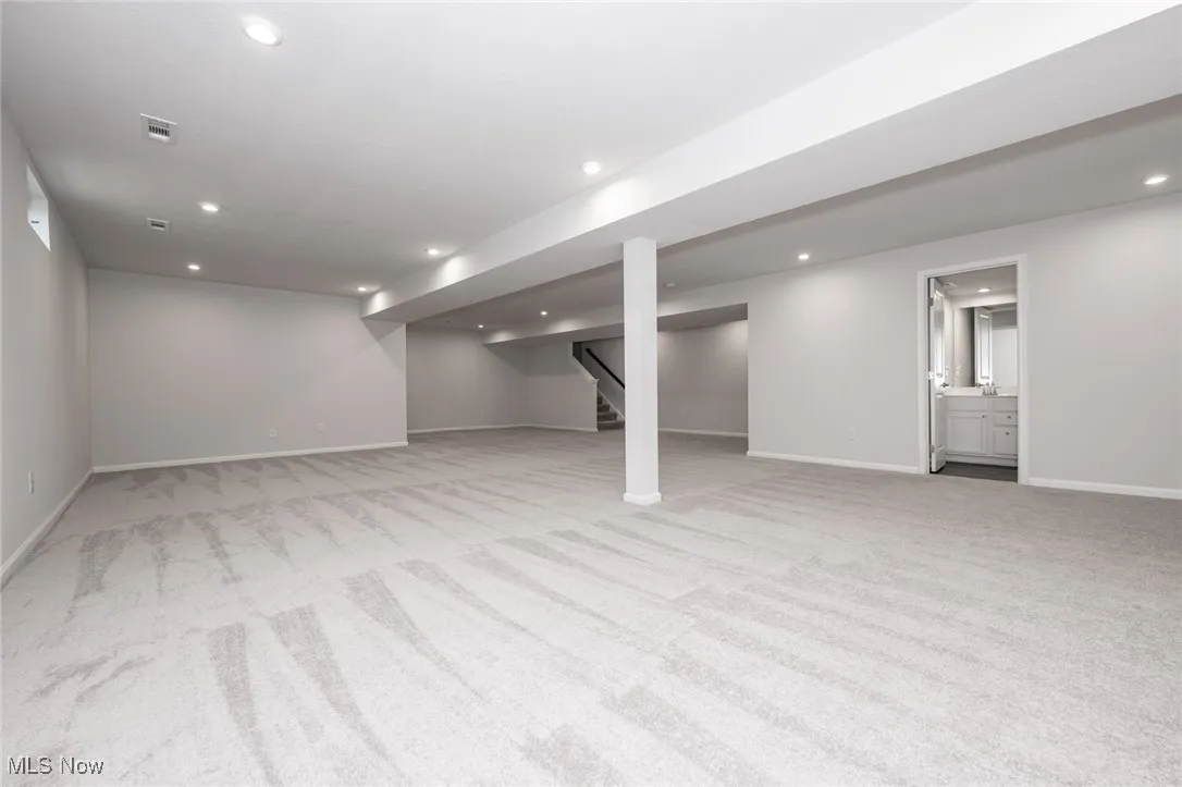 Finished below grade area featuring light carpet, recessed lighting, and stairway