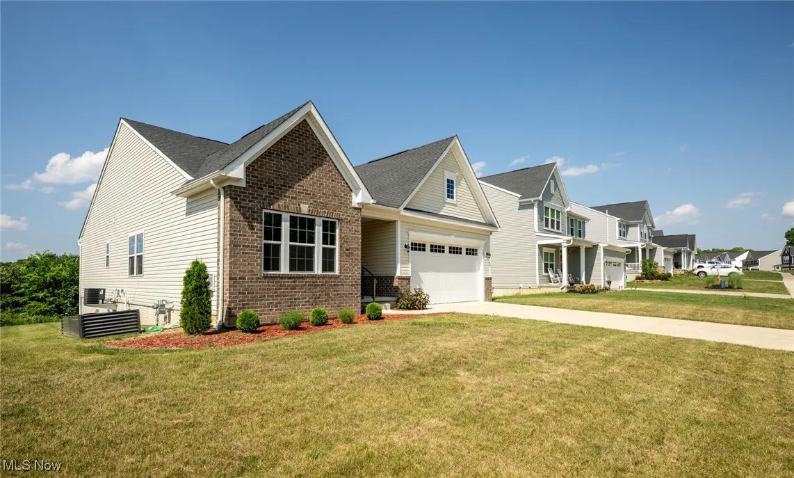 View of front of property with brick siding, driveway, an attached garage, and a front yard