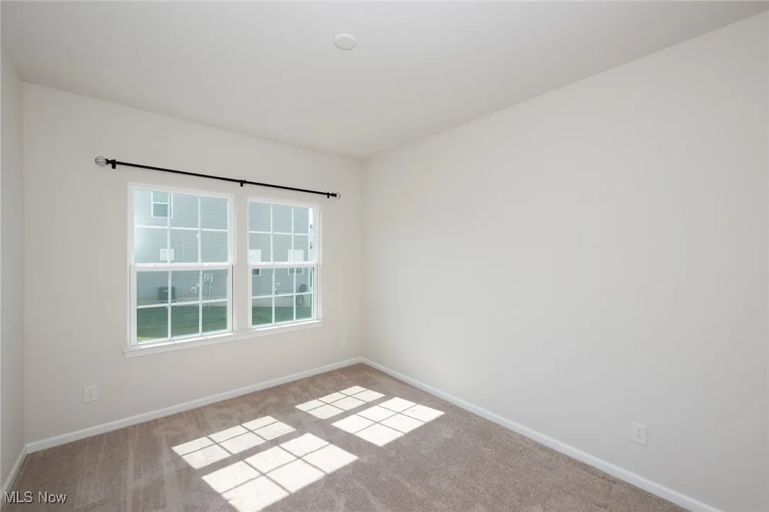 Carpeted spare room featuring baseboards