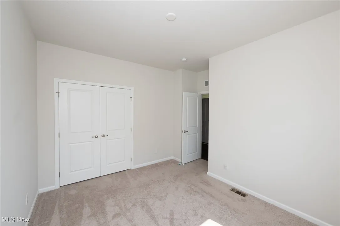 Unfurnished bedroom with light colored carpet and a closet