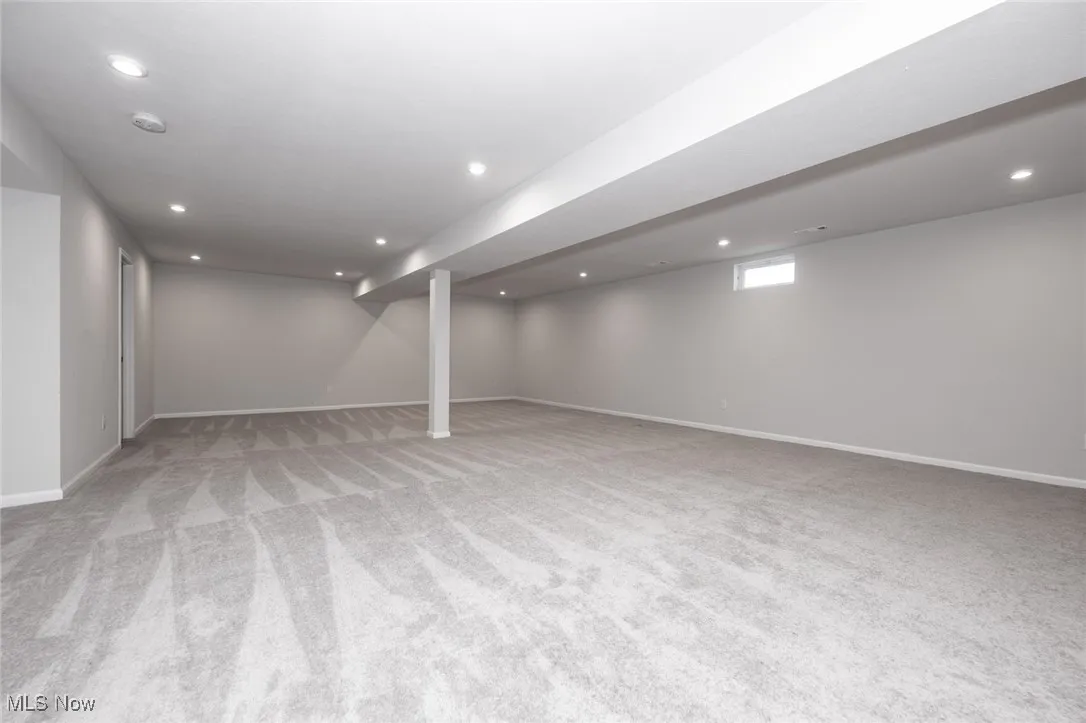 Below grade area with light colored carpet and recessed lighting