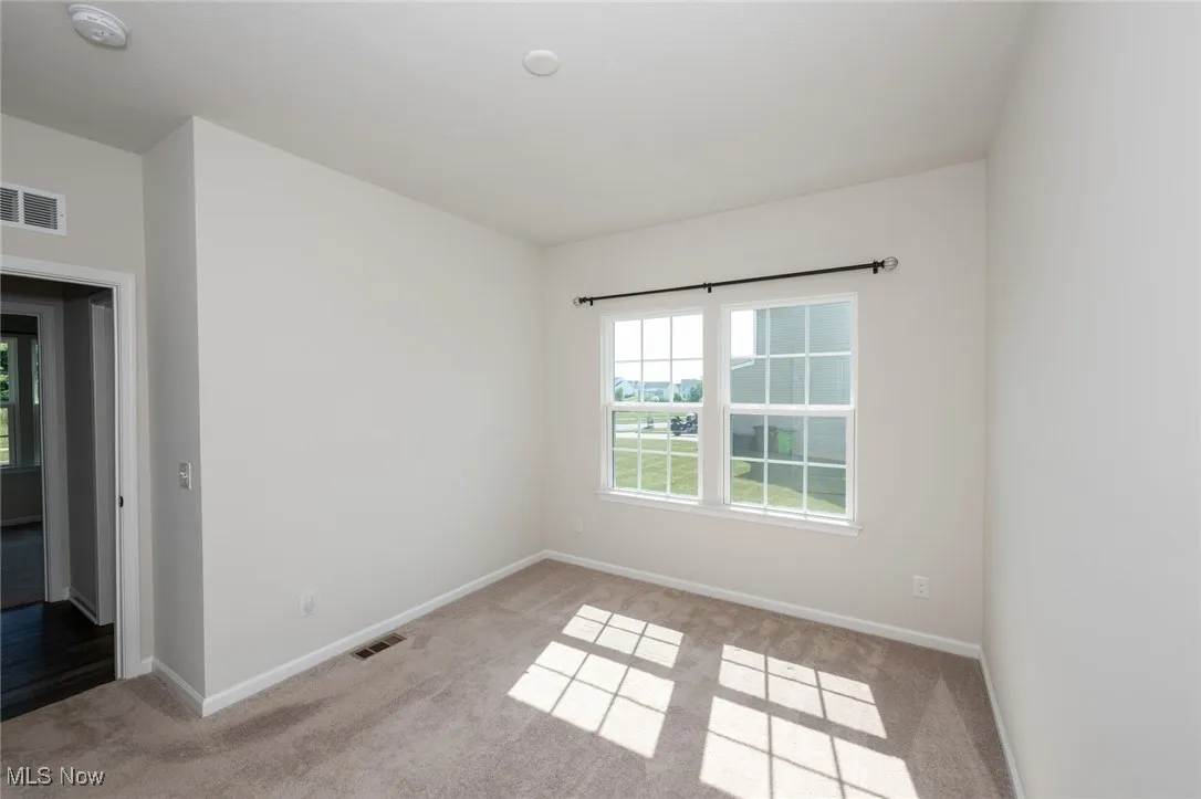 Empty room with a smoke detector and light carpet