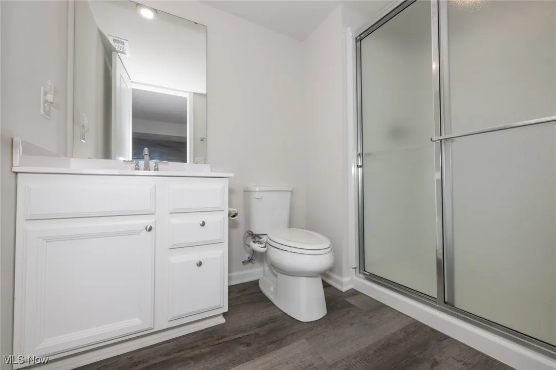 Bathroom with a shower with door, vanity, and wood finished floors