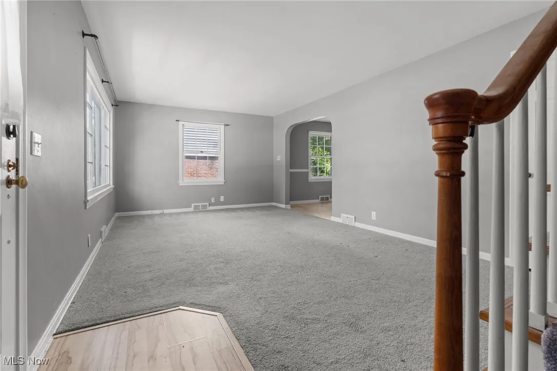 Unfurnished room with arched walkways and carpet floors