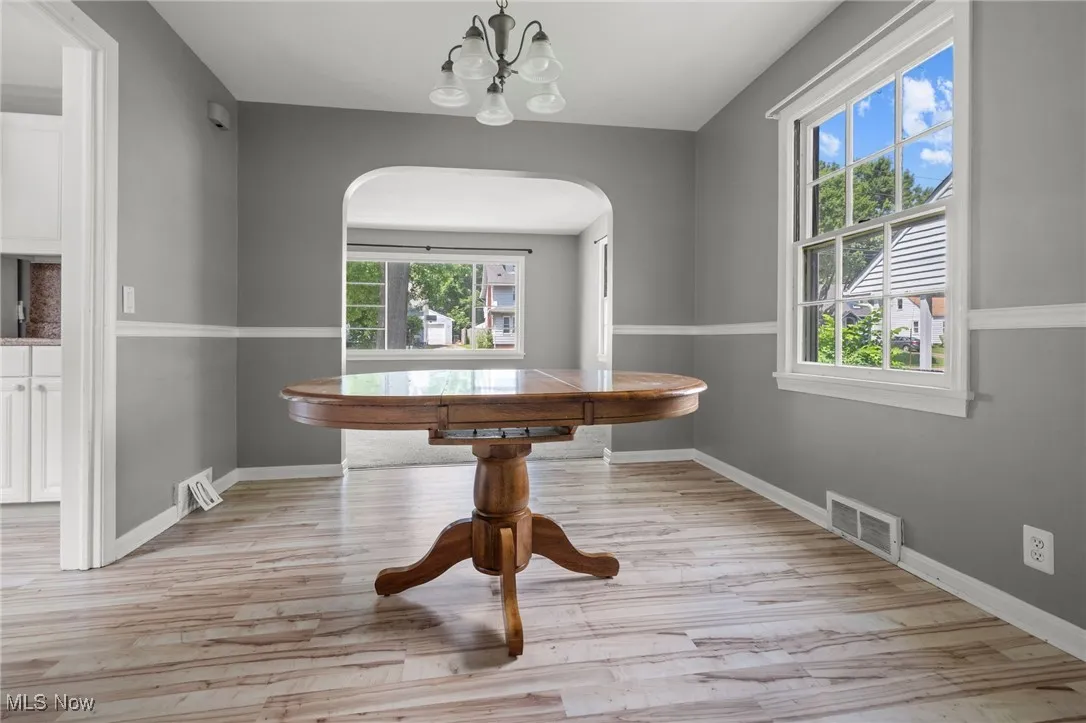 Unfurnished dining area featuring arched walkways, healthy amount of natural light, and light wood-style floors