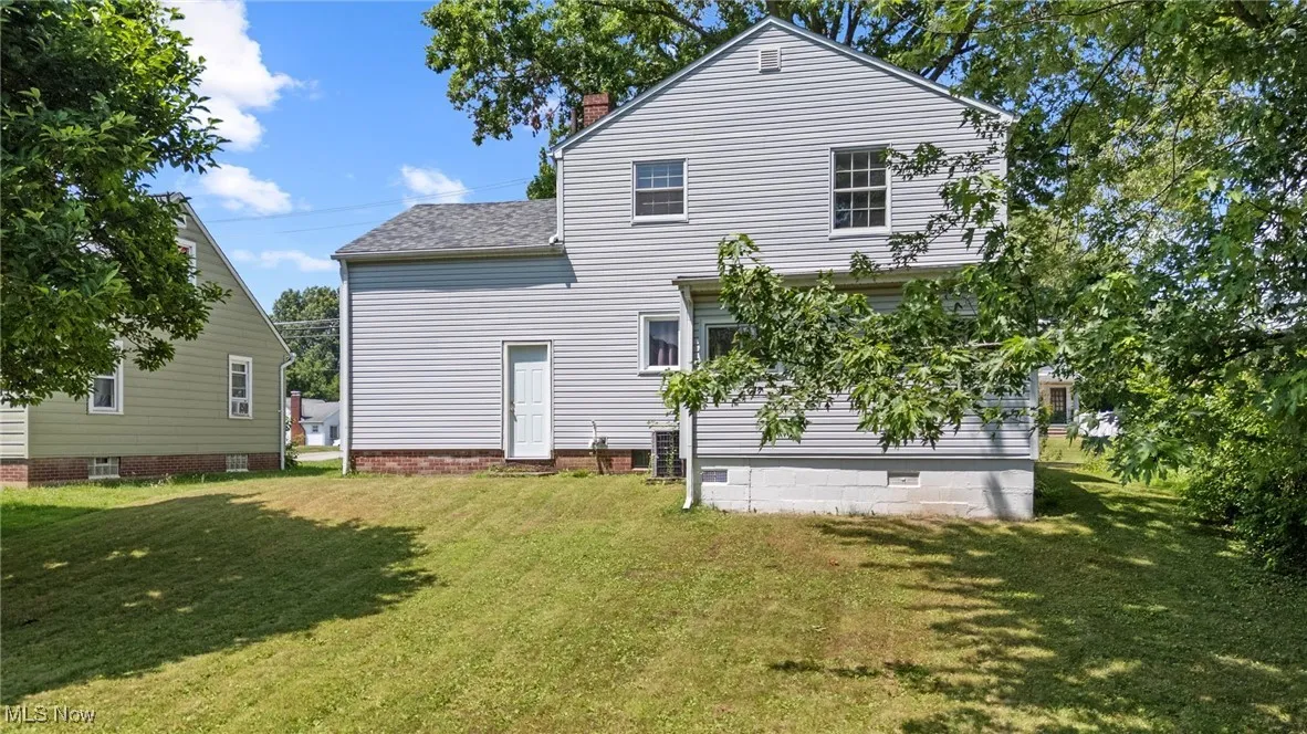 Rear view of house featuring a yard, a chimney, crawl space, and roof with shingles