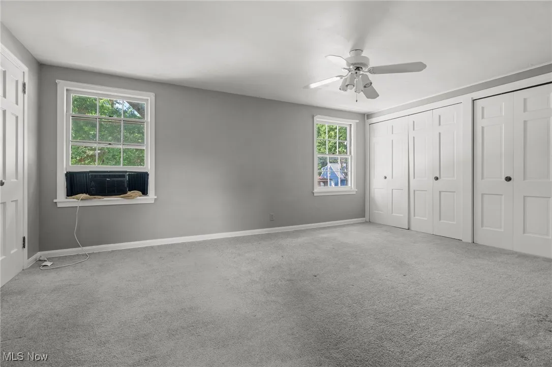 Unfurnished bedroom with cooling unit, multiple closets, carpet flooring, and ceiling fan