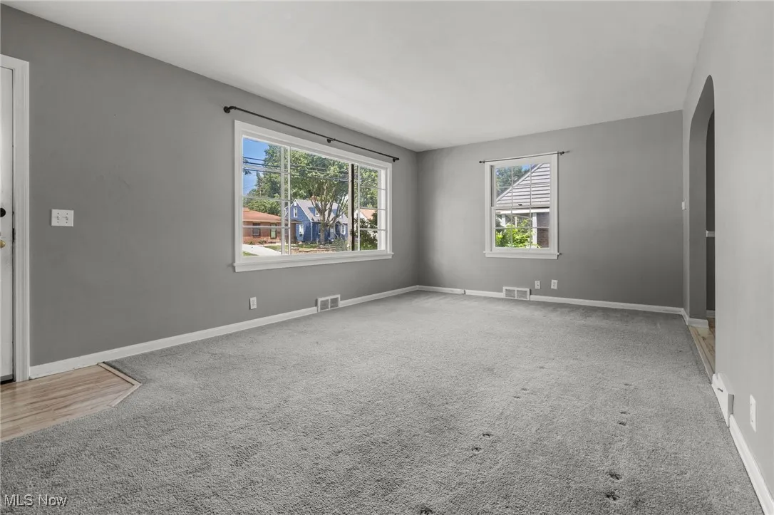 Unfurnished room featuring arched walkways, plenty of natural light, and carpet floors