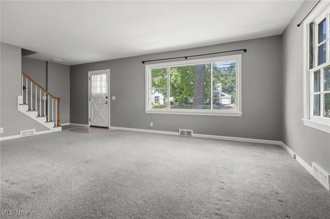Carpeted foyer entrance featuring stairway and baseboards