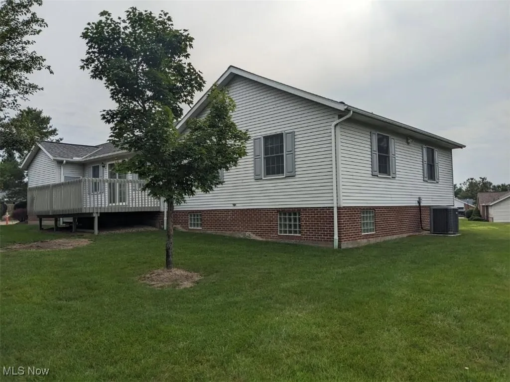 View of side of home with a yard and a wooden deck