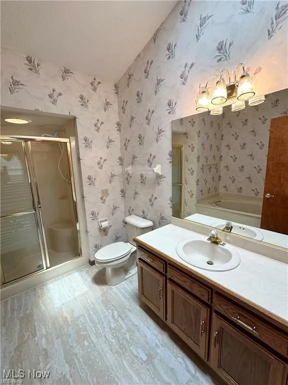 Full bath featuring wallpapered walls, vanity, a stall shower, a garden tub