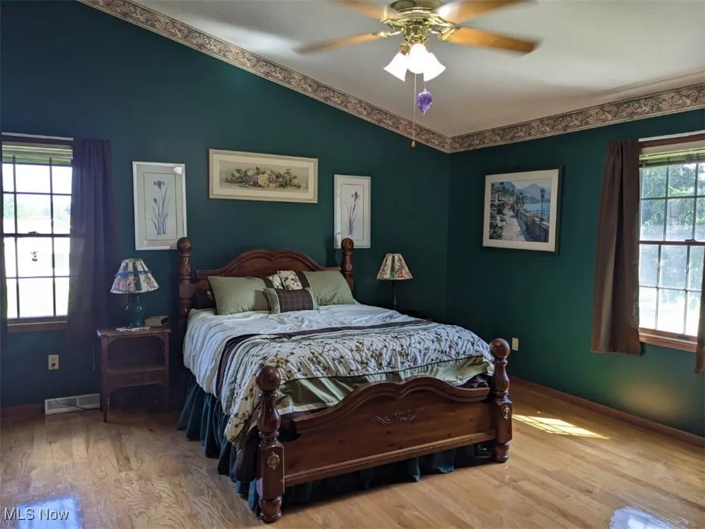 Bedroom featuring wood finished floors, lofted ceiling, and ceiling fan