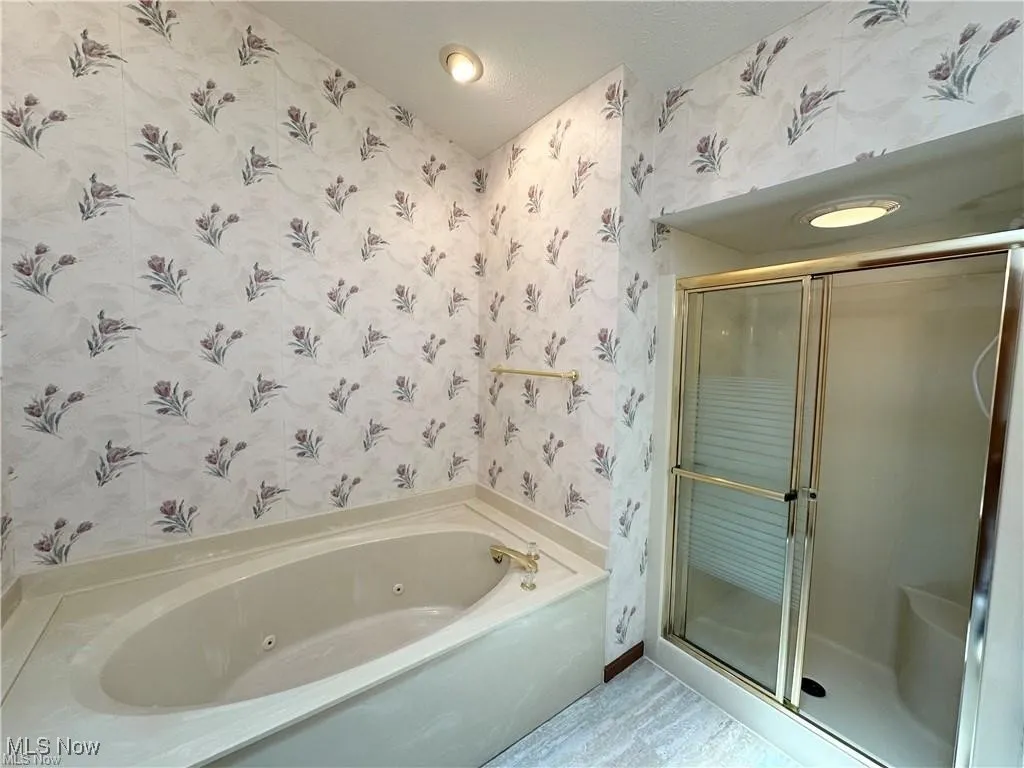 Bathroom featuring wallpapered walls, a stall shower, and a jetted tub